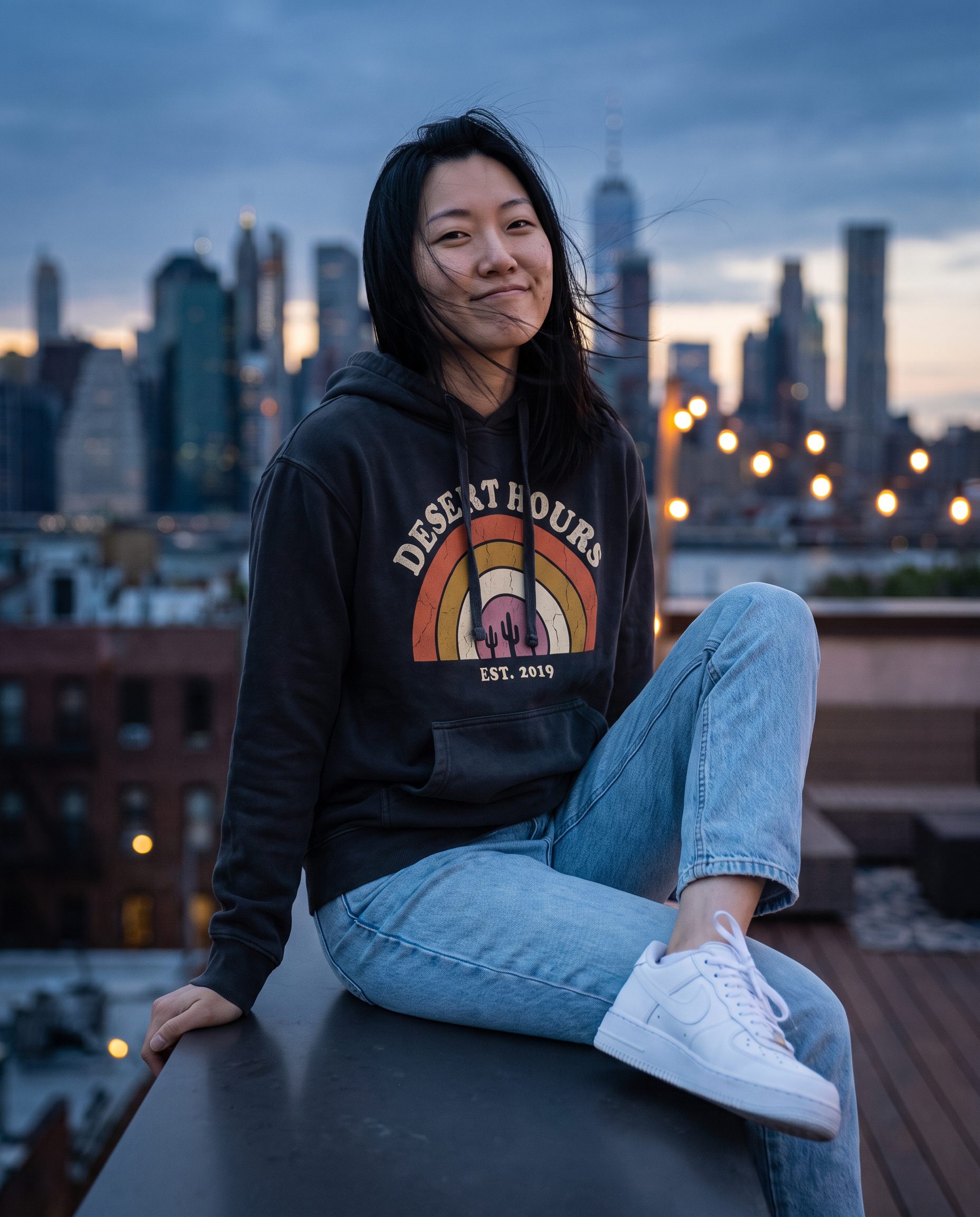 Mei in the Desert Hours hoodie on a rooftop at dusk